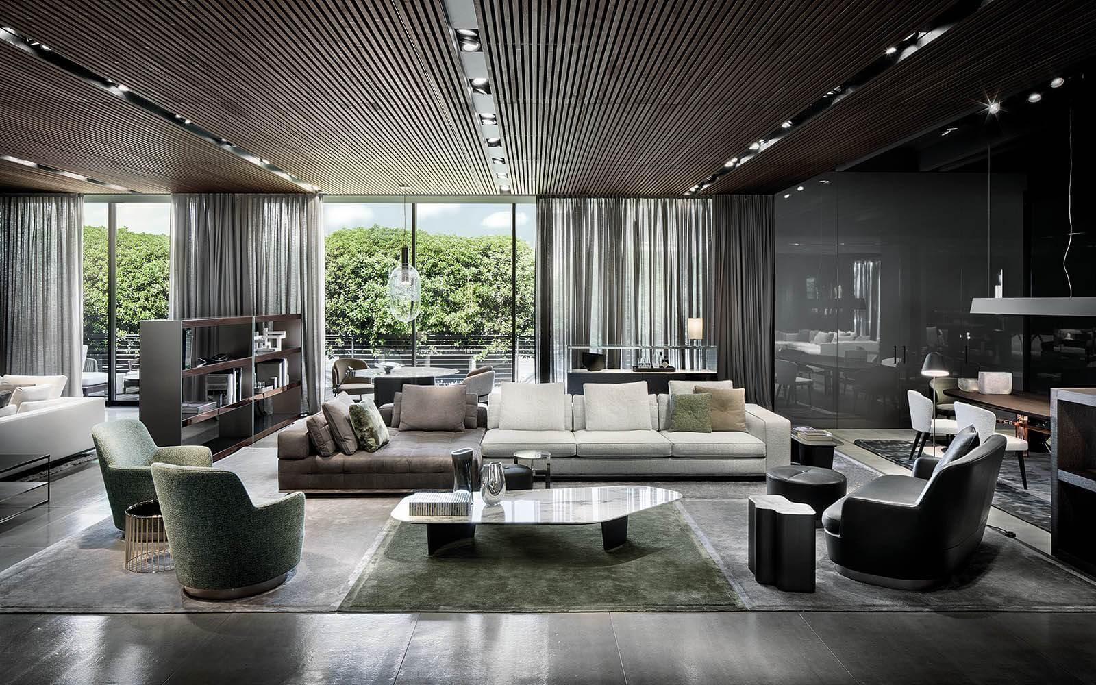 Modern luxury living room with sheer curtains, large sectional sofa, accent chairs, marble coffee table, soft area rugs, and floor to ceiling windows overlooking greenery.