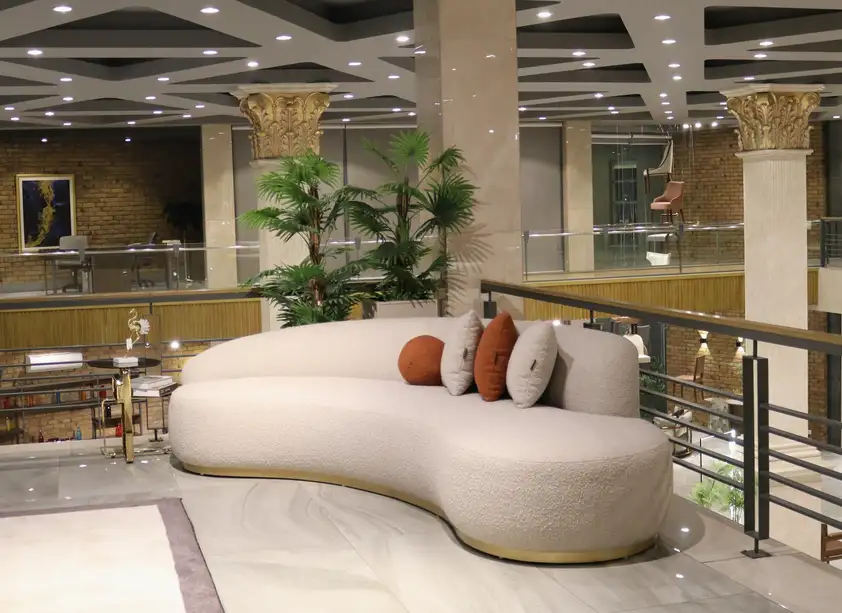 modern curved luxury sofa design in Pakistan with cream fabric and decorative cushions in stylish interior